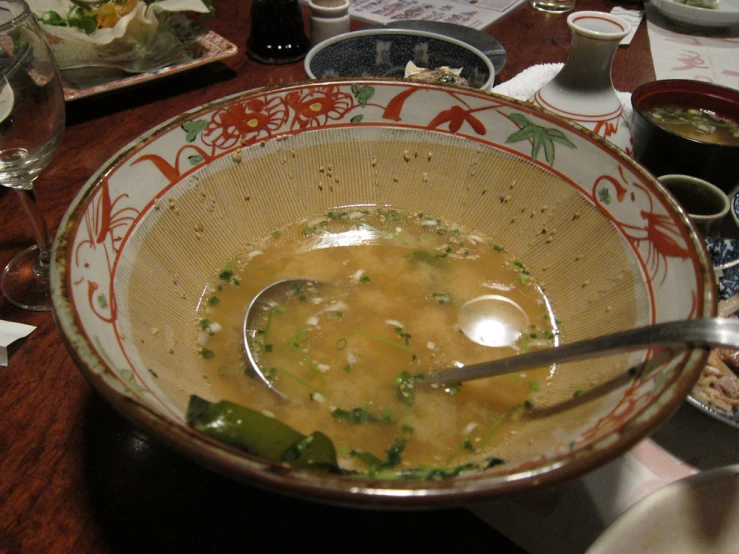 a bowl with soup sits on a table near wine glasses