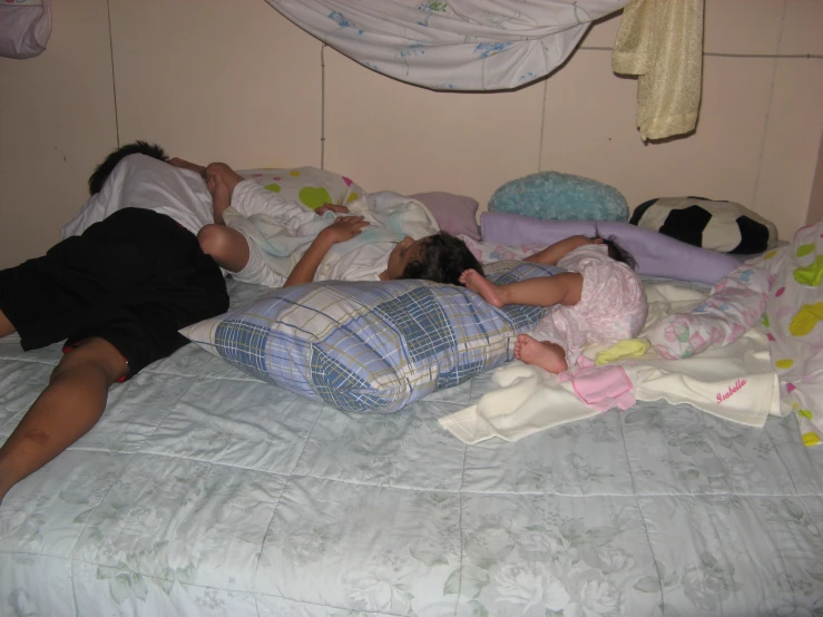 a couple of children laying on pillows in a bed