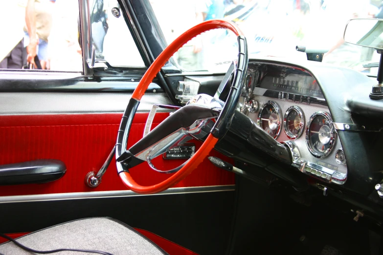 a red and black old car with an orange steering wheel