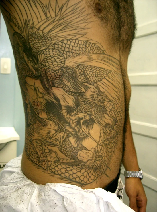 this is a man's lower back with a dragon tattooed on his stomach