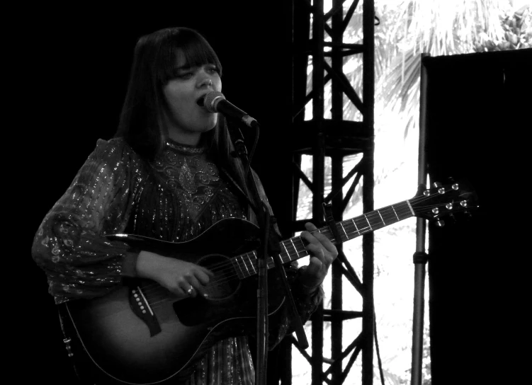 a woman with long black hair playing the guitar on stage