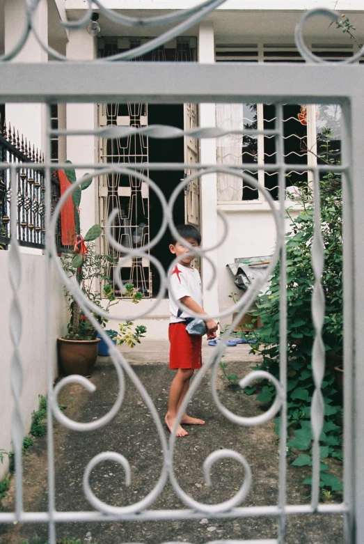 a man in red shorts stands outside of a house