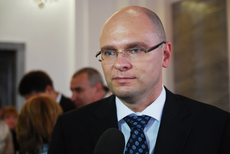 a balding man is looking at soing while wearing a suit and tie