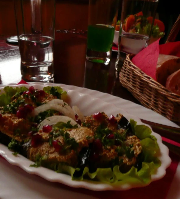 a salad in a paper plate with a glass of water