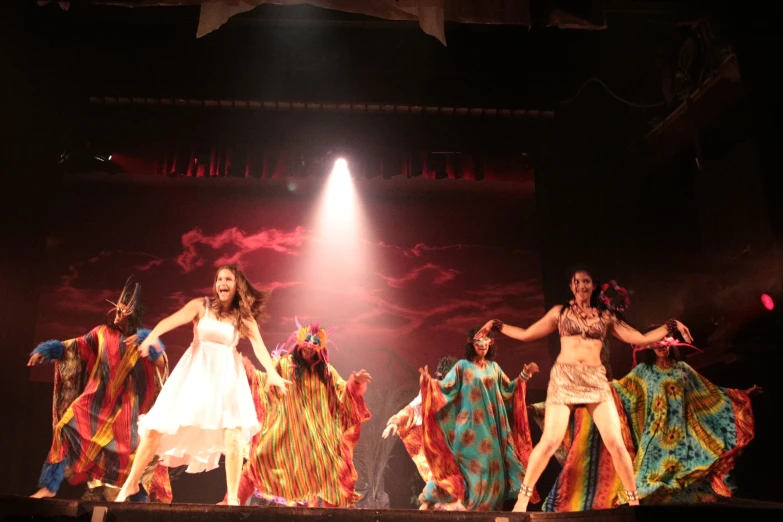 a group of women perform on stage with lights on the side