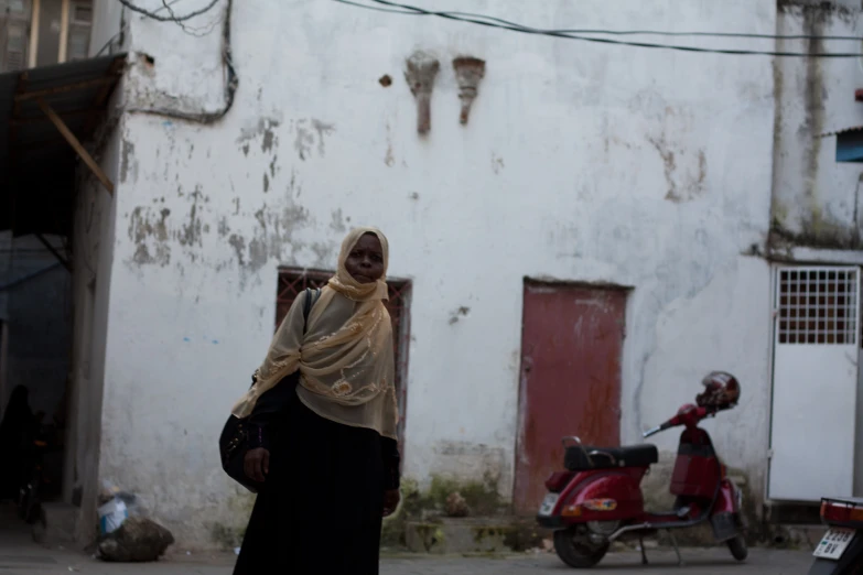 a woman walking down a street wearing a shawl