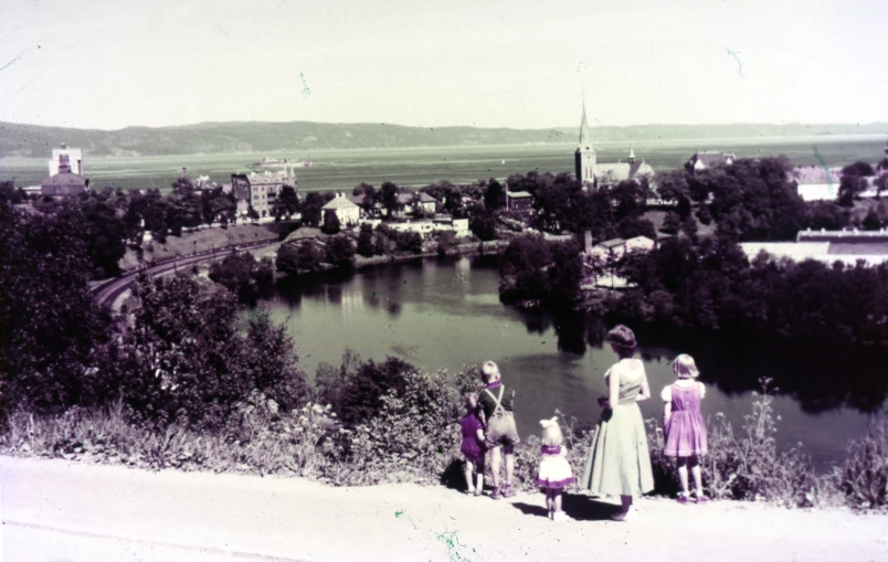 people standing on top of a hill by a body of water