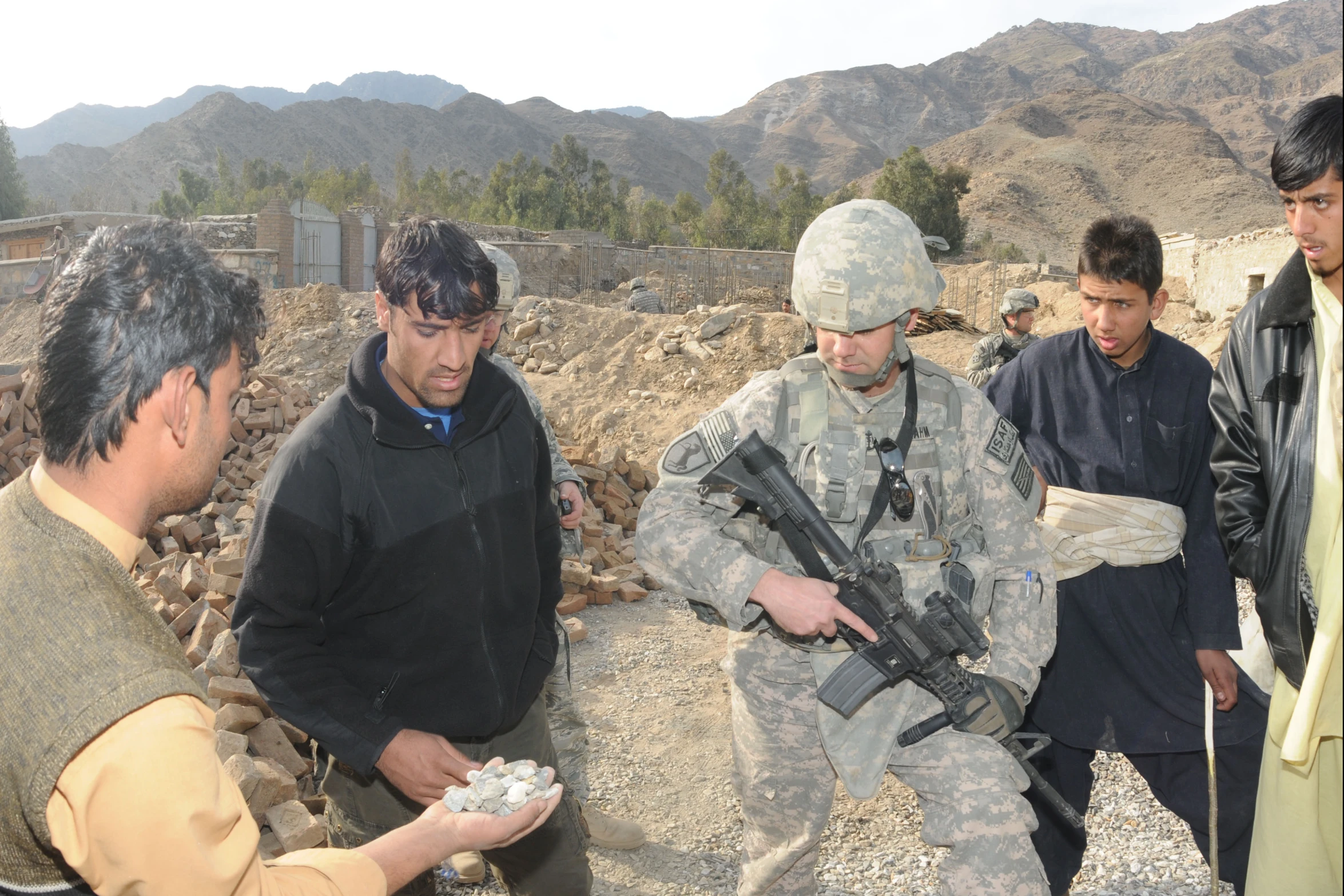 men standing around one of the soldiers holds a gun