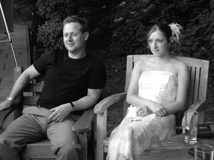 a man and a woman sitting on wooden chairs