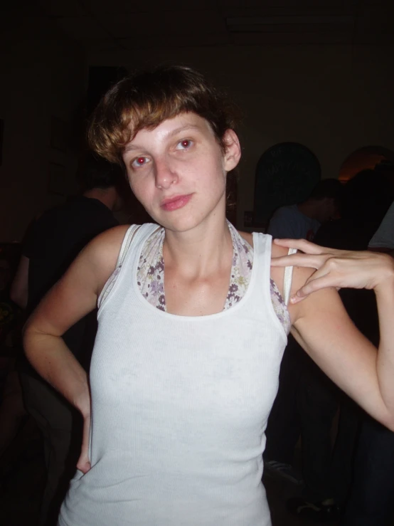 a young lady wearing a white tank top in front of a group