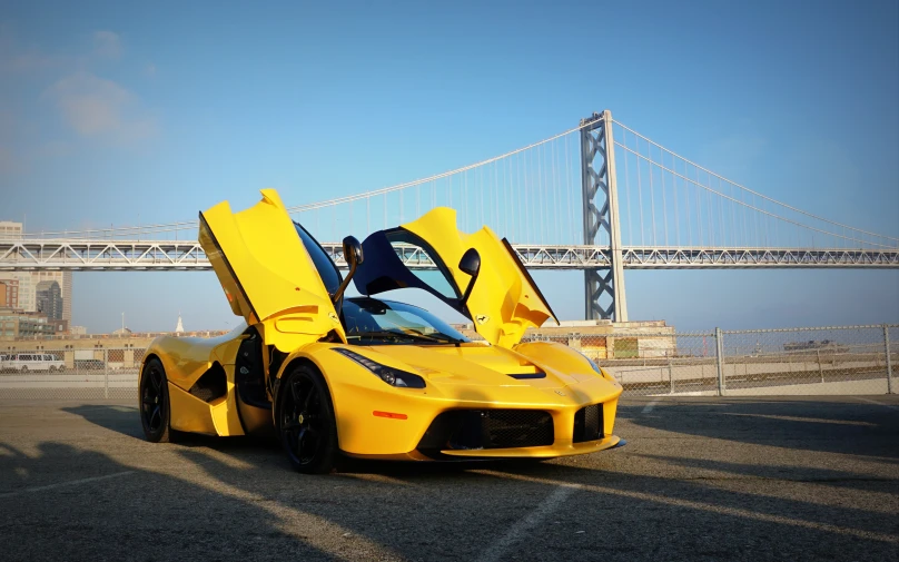 a sports car parked near the water and the bridge