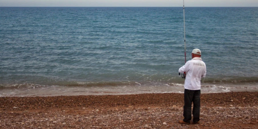 a man standing on a beach holding a fishing line