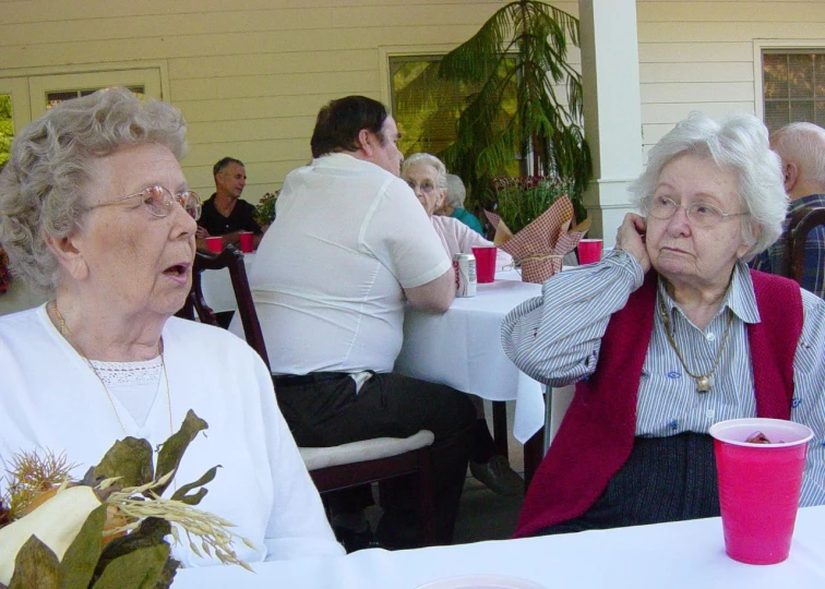 two elderly women sitting at tables at a cafe