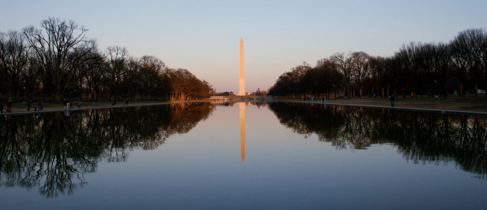 the washington monument is reflected in the still water of a lake