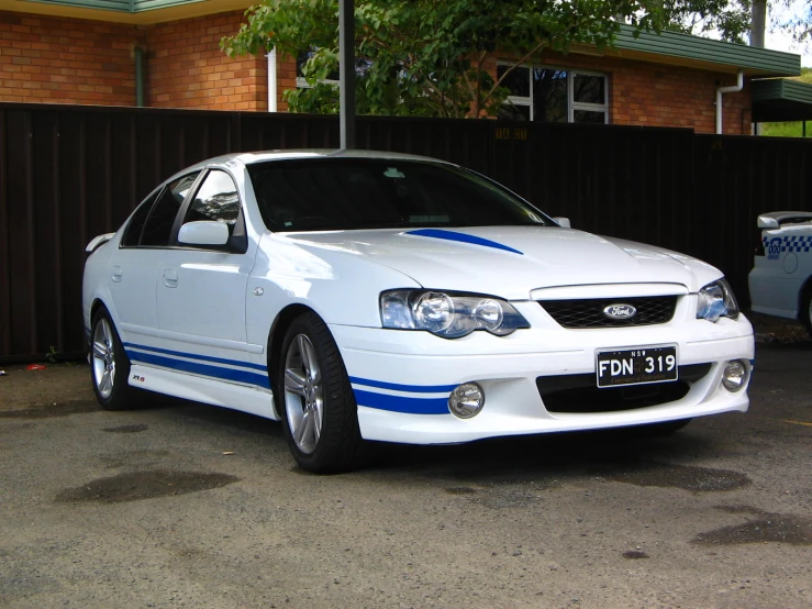 a white car with blue stripes parked on the street