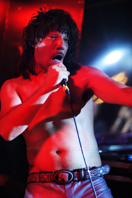 a shirtless man standing on a stage with microphone