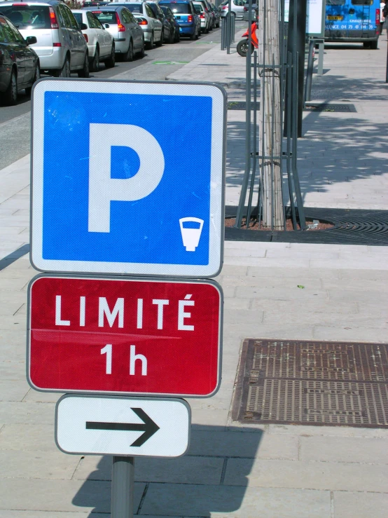 a street sign next to a sidewalk with parking spaces nearby