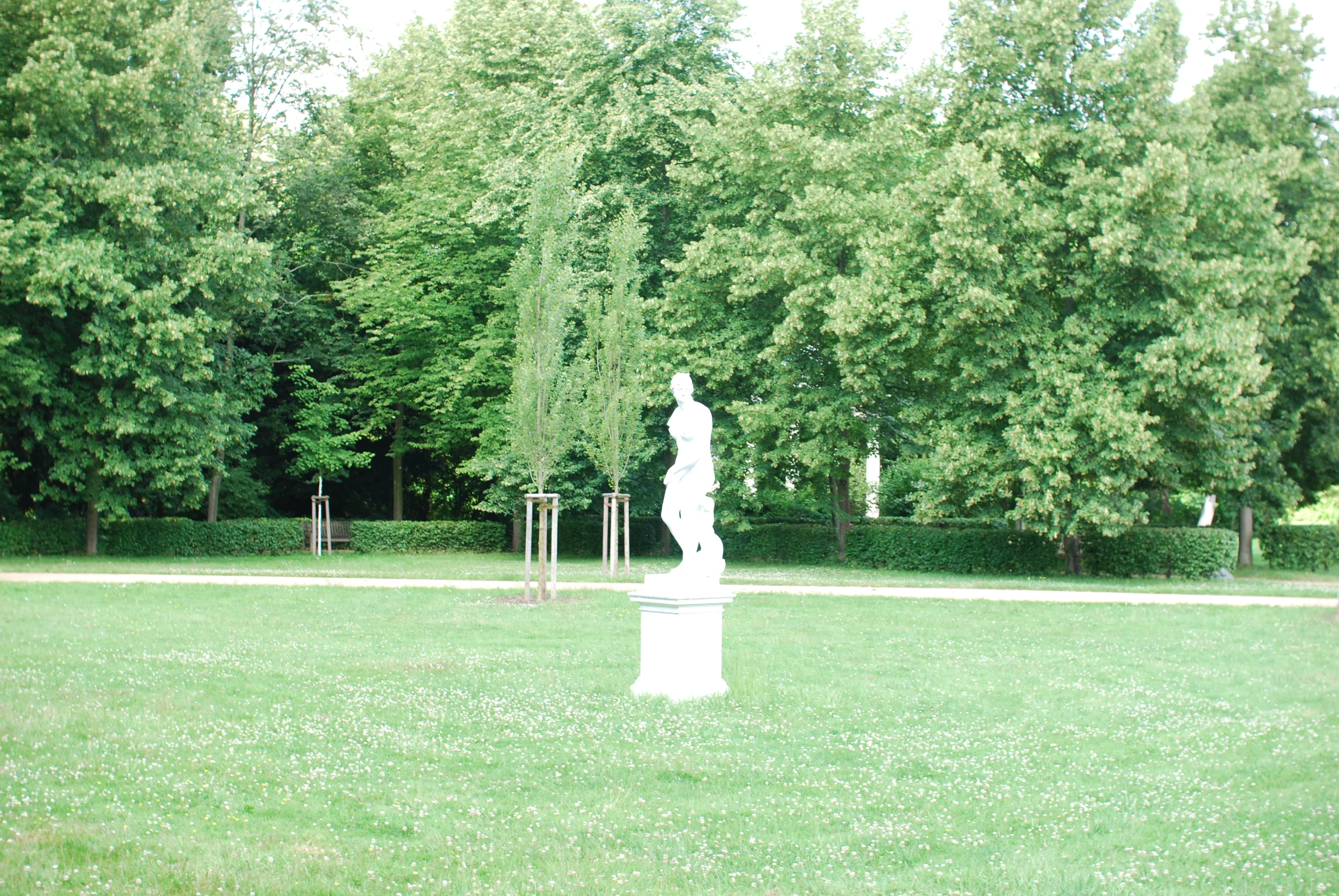 a sculpture sits in a park with trees in the background