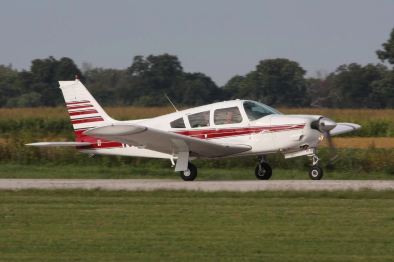 a small white airplane with a red and white striped tail is on the runway