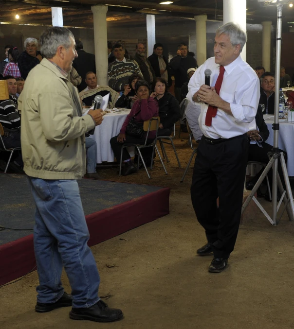 two men in dress shirts and ties speaking to each other