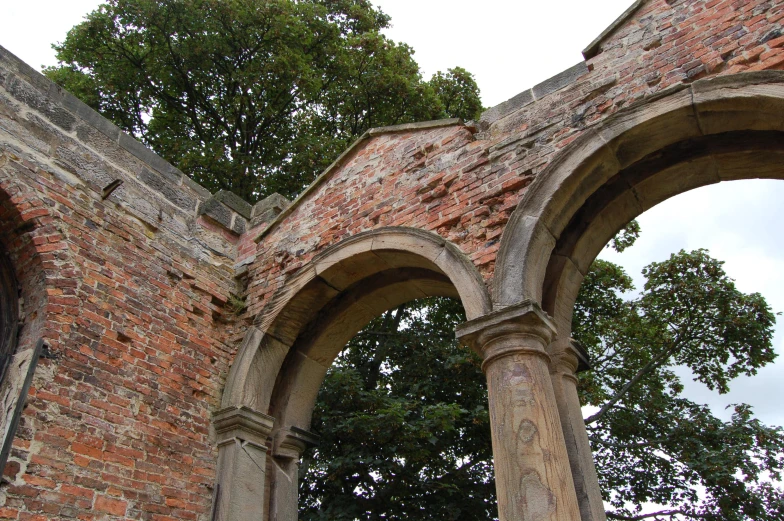 a pair of old stone arches with trees behind