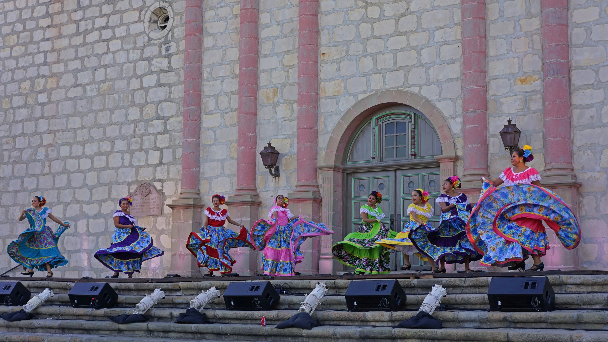 a group of woman dance on steps in front of a stone building