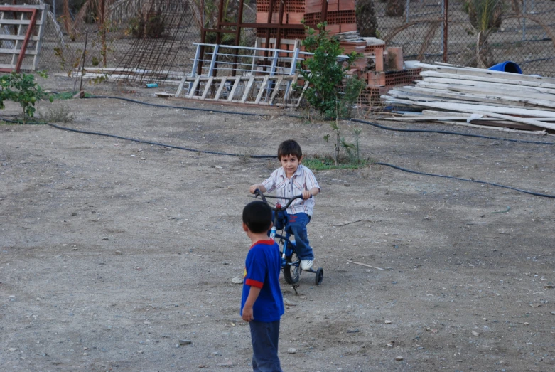 two children playing on their bikes in the dirt