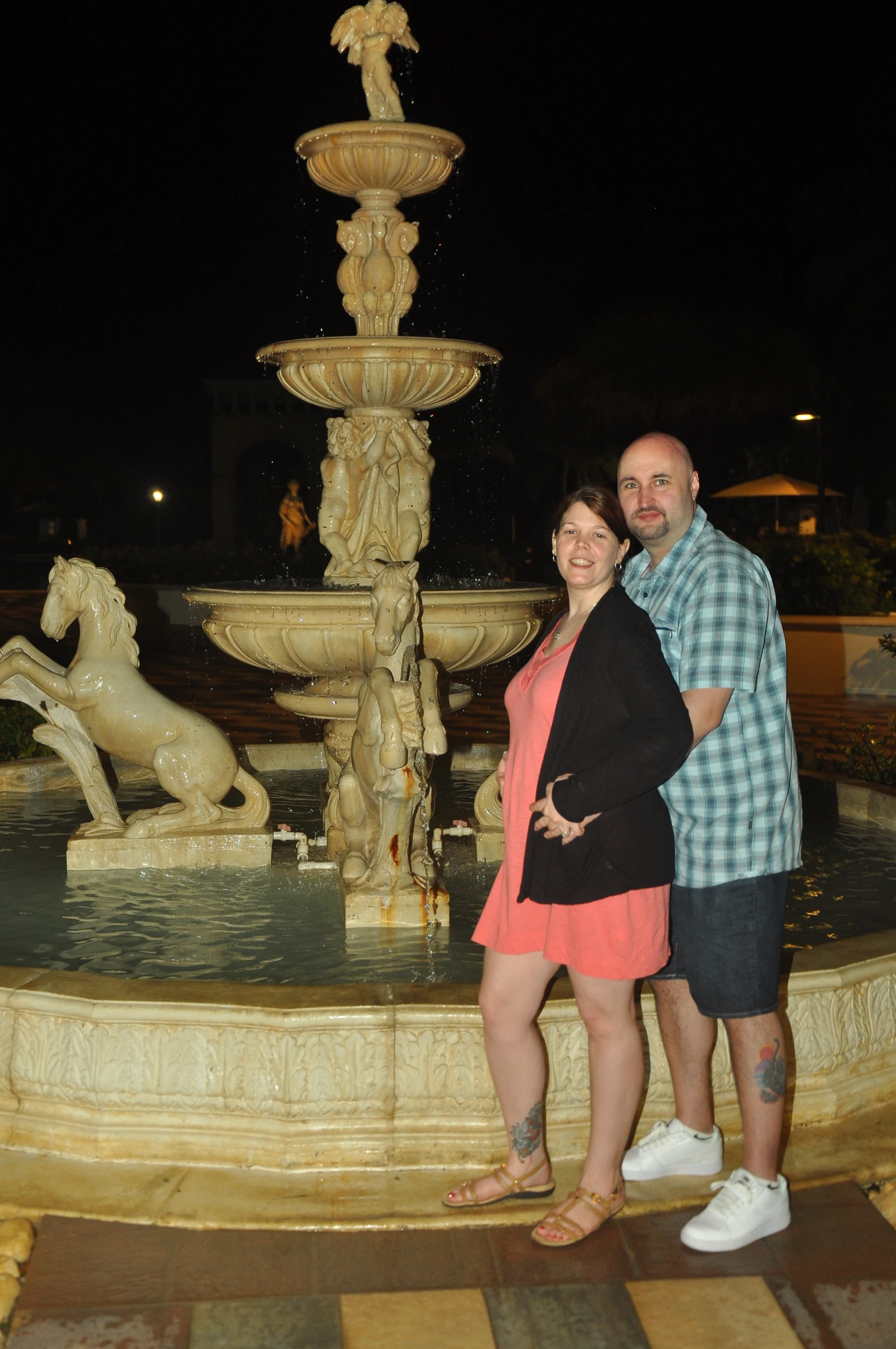 the couple pose for a po near a water fountain