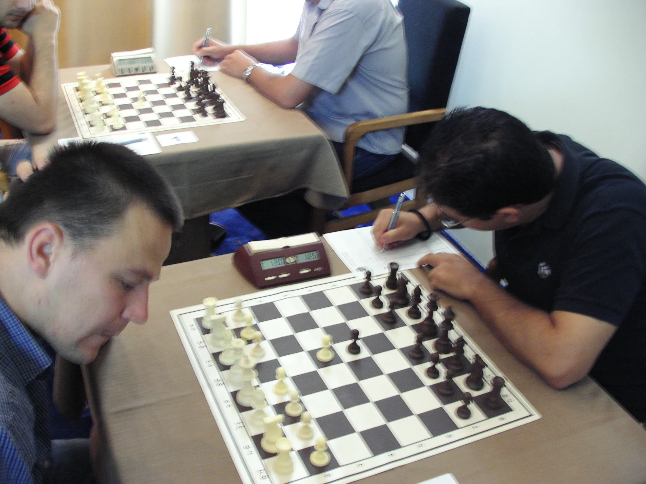 three men playing chess at an open room