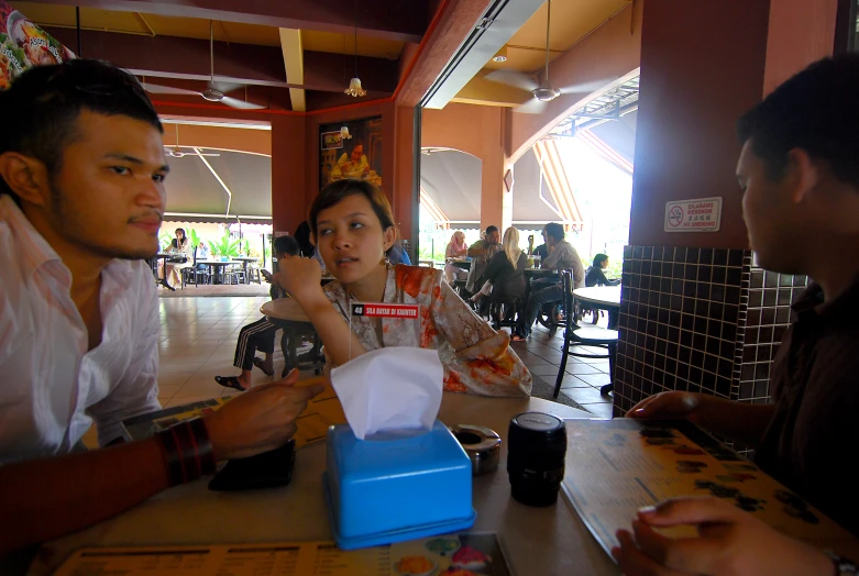 three people are sitting at a table eating