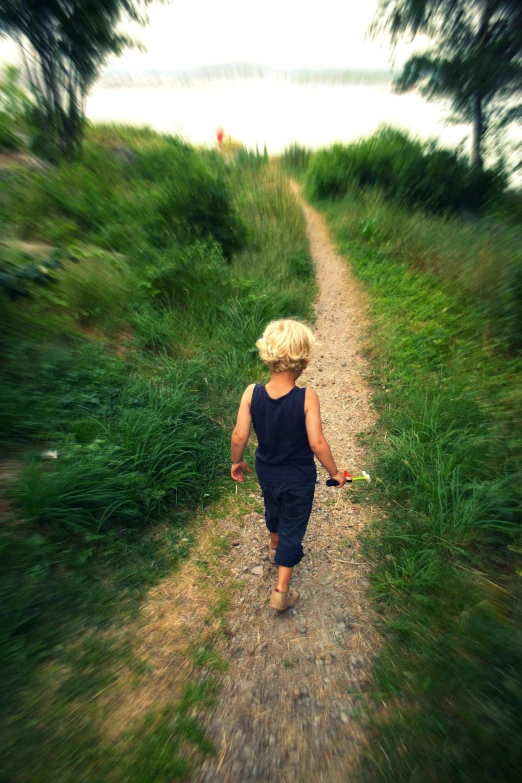 a little boy walking down a dirt road