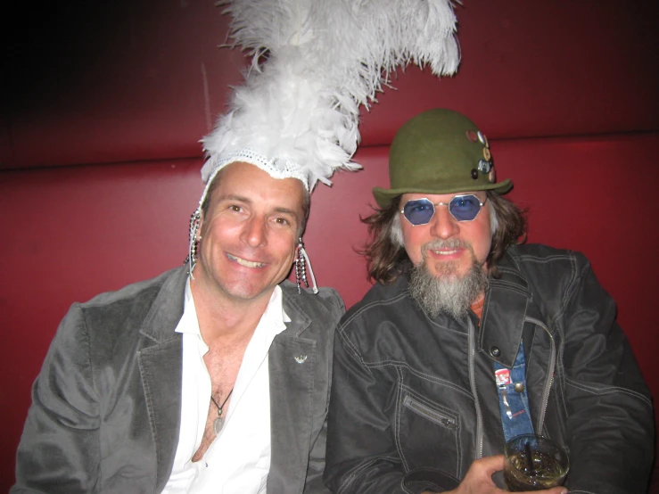 two men posing for a picture wearing feather hats and glasses