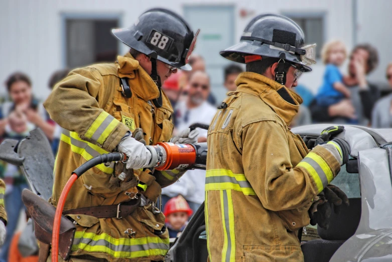 two firemen standing next to a white car