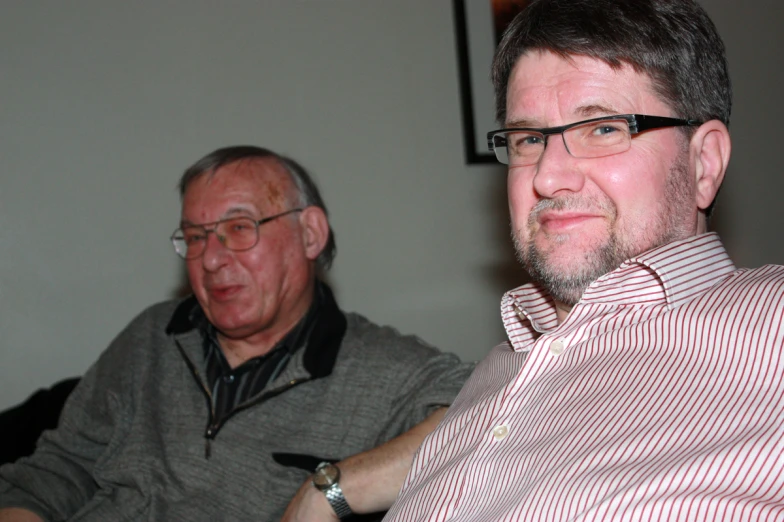 two men sit together in the living room