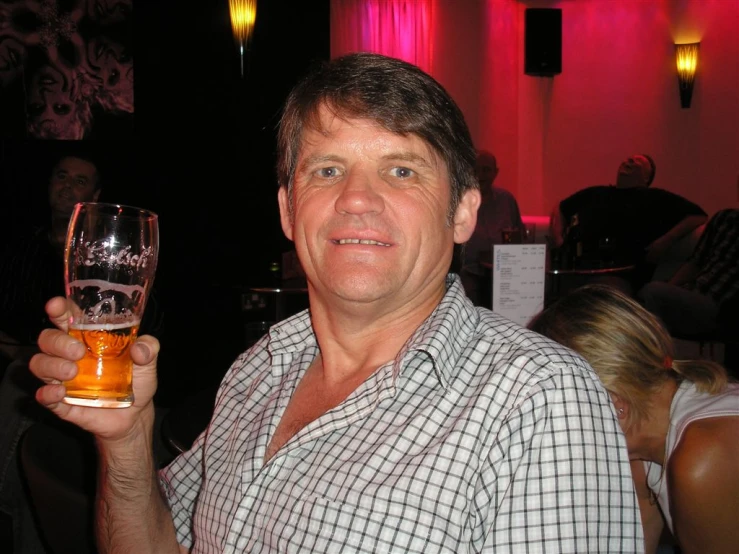 a man smiles while holding a glass of wine