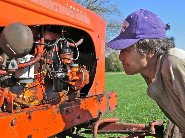 an old man is inspecting a old type of tractor