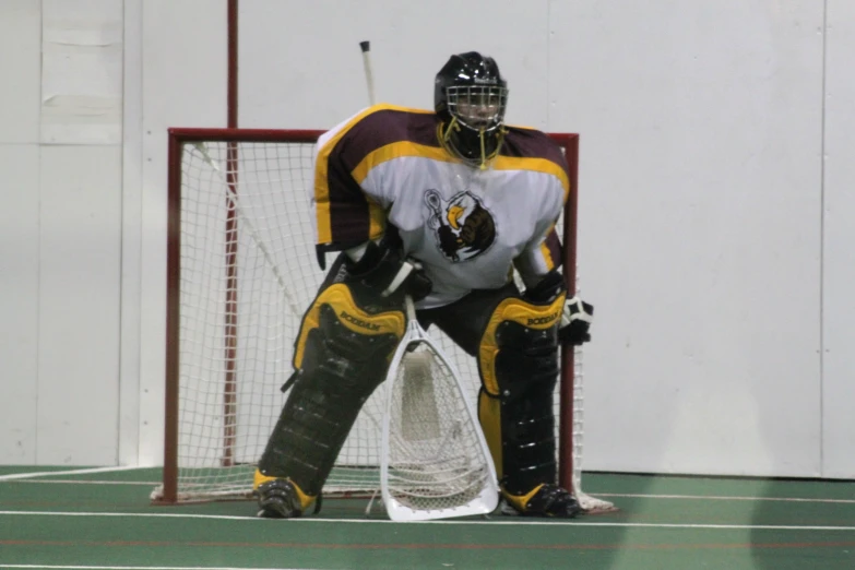 a hockey player crouched down on the ice, waiting to hit the ball