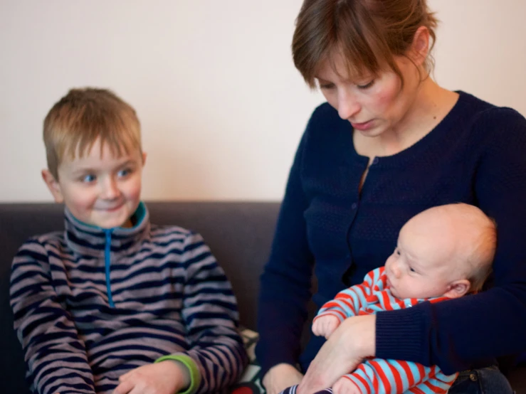 woman holding two boys with baby's arms