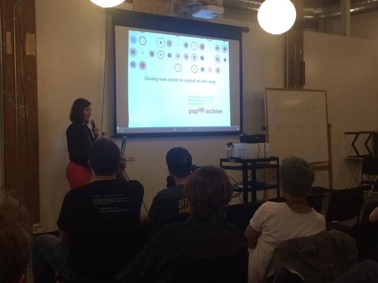 a group of people sitting down in front of a projector screen