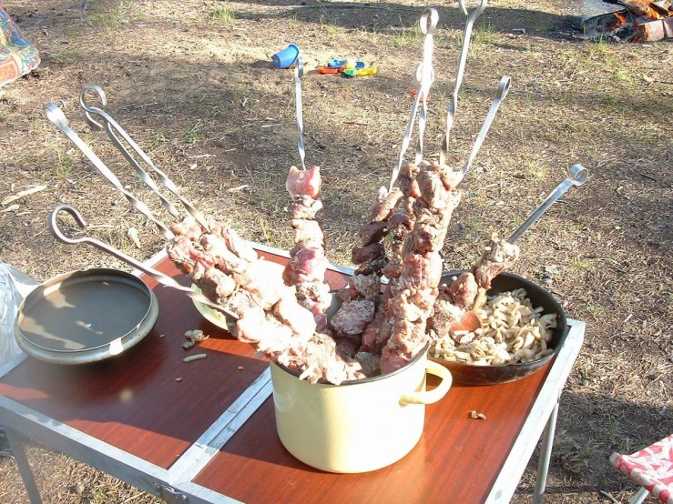 a group of meat and utensils sticking out of the middle of a table