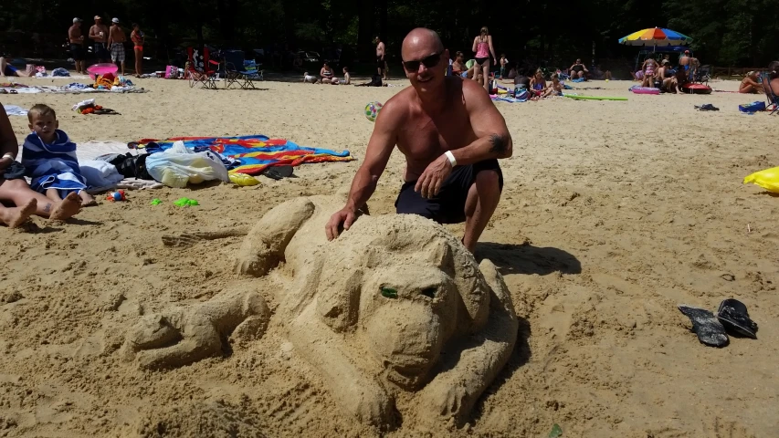 man sitting in the sand by a face made out of sand