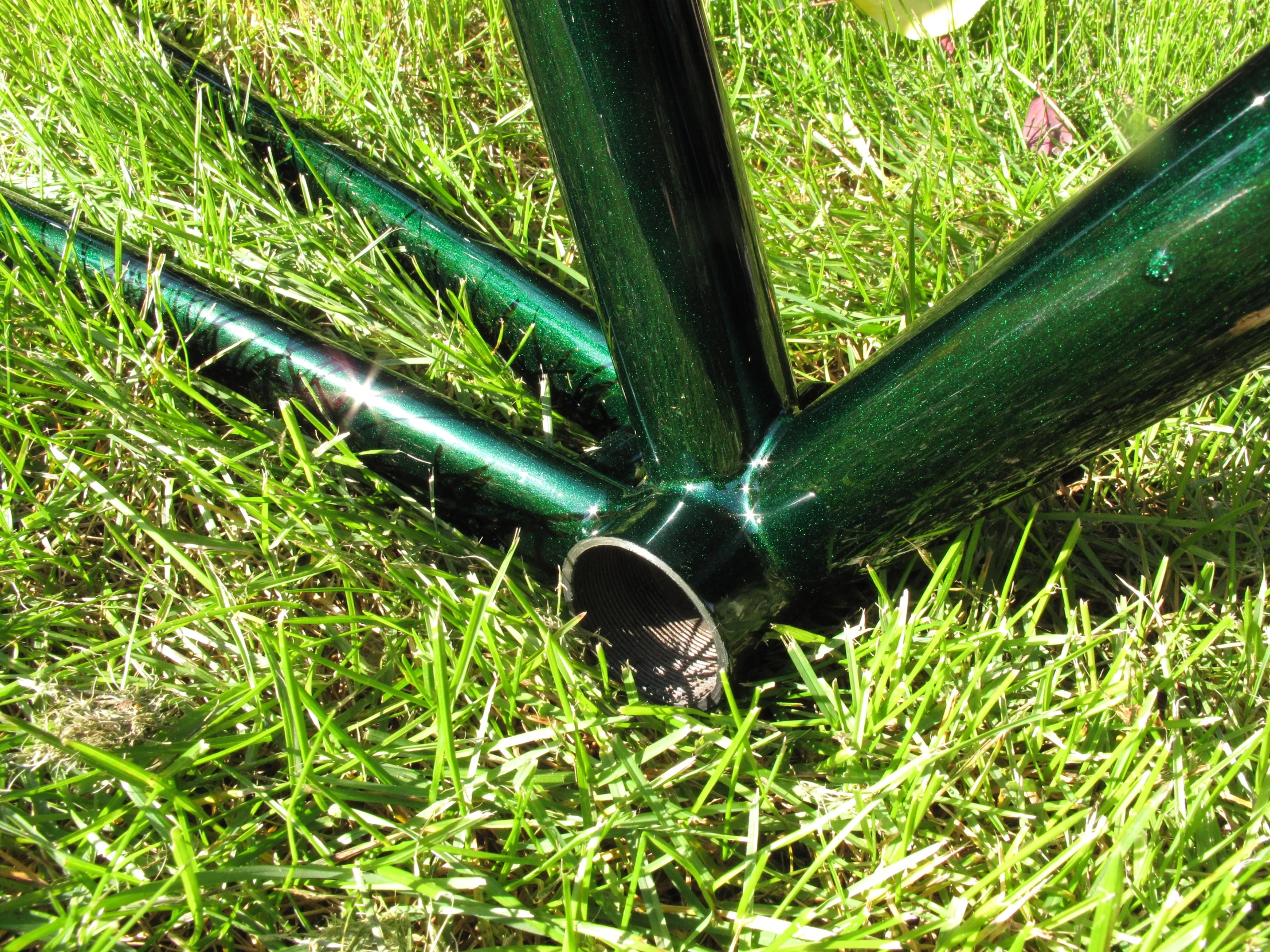 a green bicycle laying on the ground on some grass