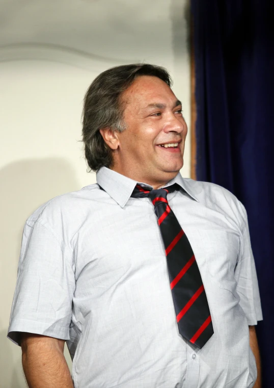 a man is laughing and wearing a black, red, and white tie