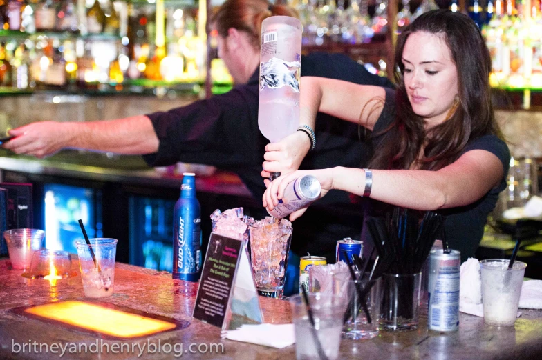 a woman pouring a drink from a bottle with an adult nearby