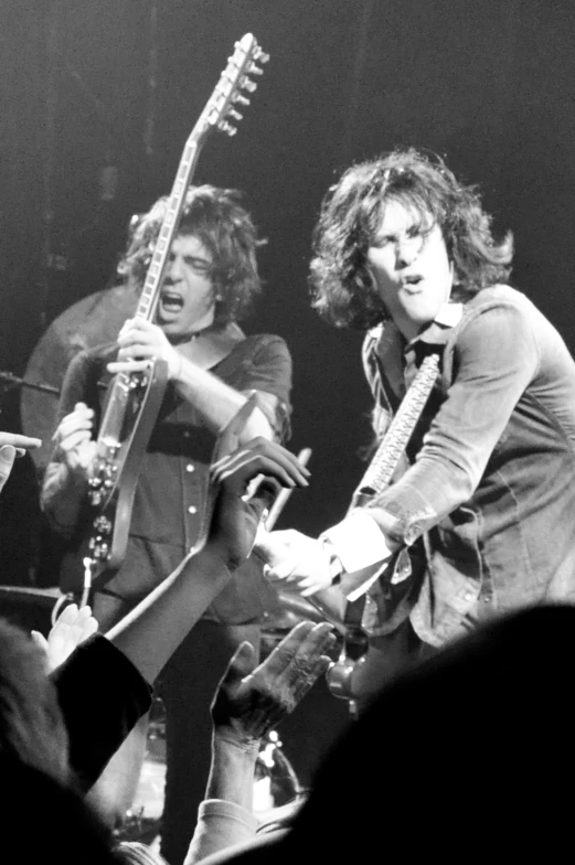 a couple of men playing guitars at a concert