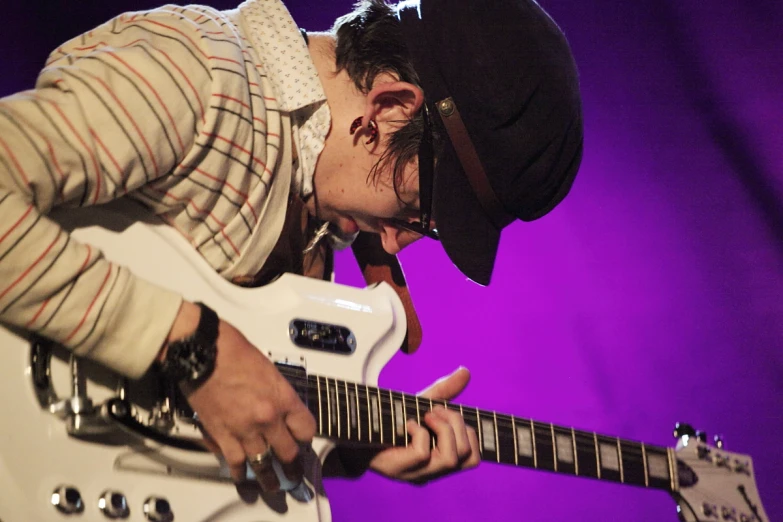 man playing guitar with purple lighting behind him