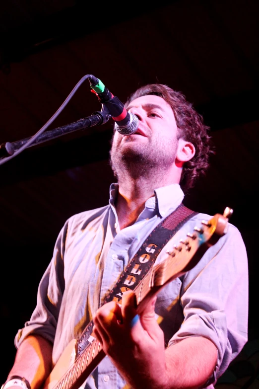 a man singing into a microphone while holding a guitar