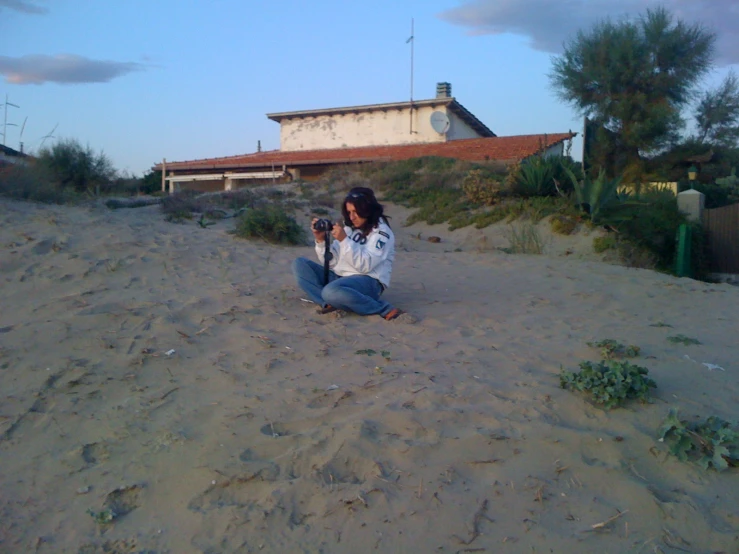 a woman sits on the beach taking a selfie