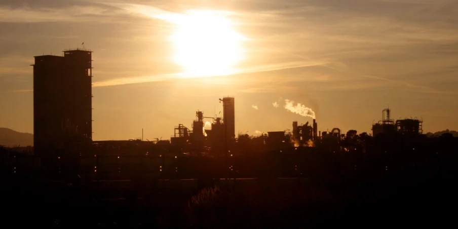 the sun is setting over factories and pipes