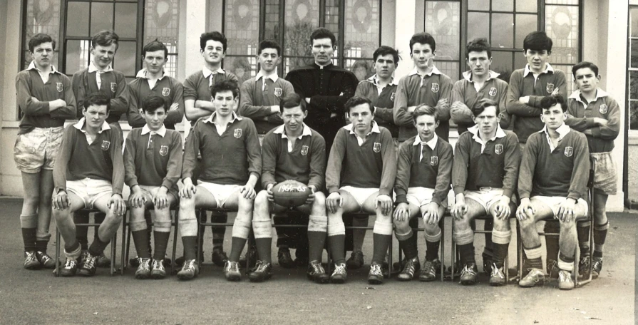 a group of young men sitting next to each other in front of a building